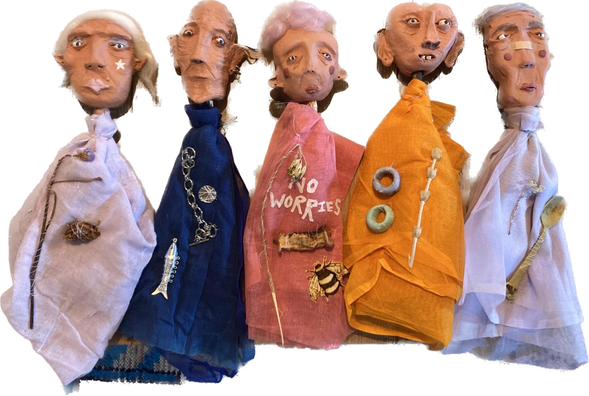 Five Worry Dolls with sculpted clay faces and fabric bodies on a white background